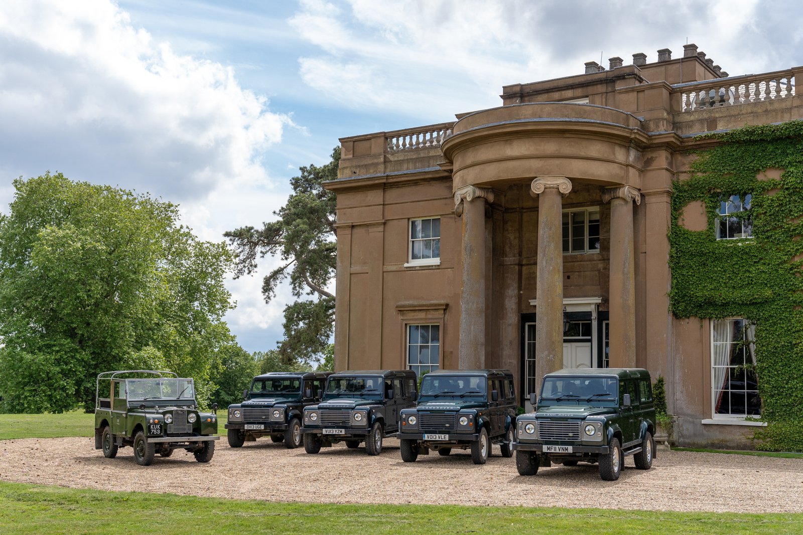 Land Rover Defenders lined up at the house