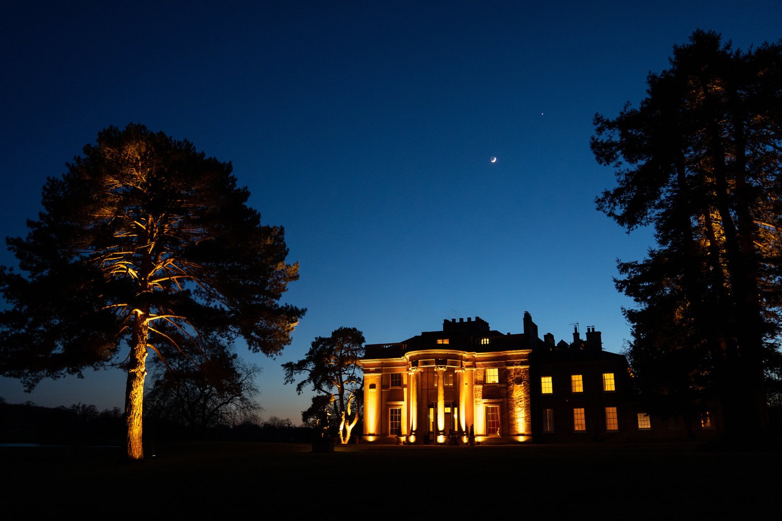 A grand country house lit at dusk
